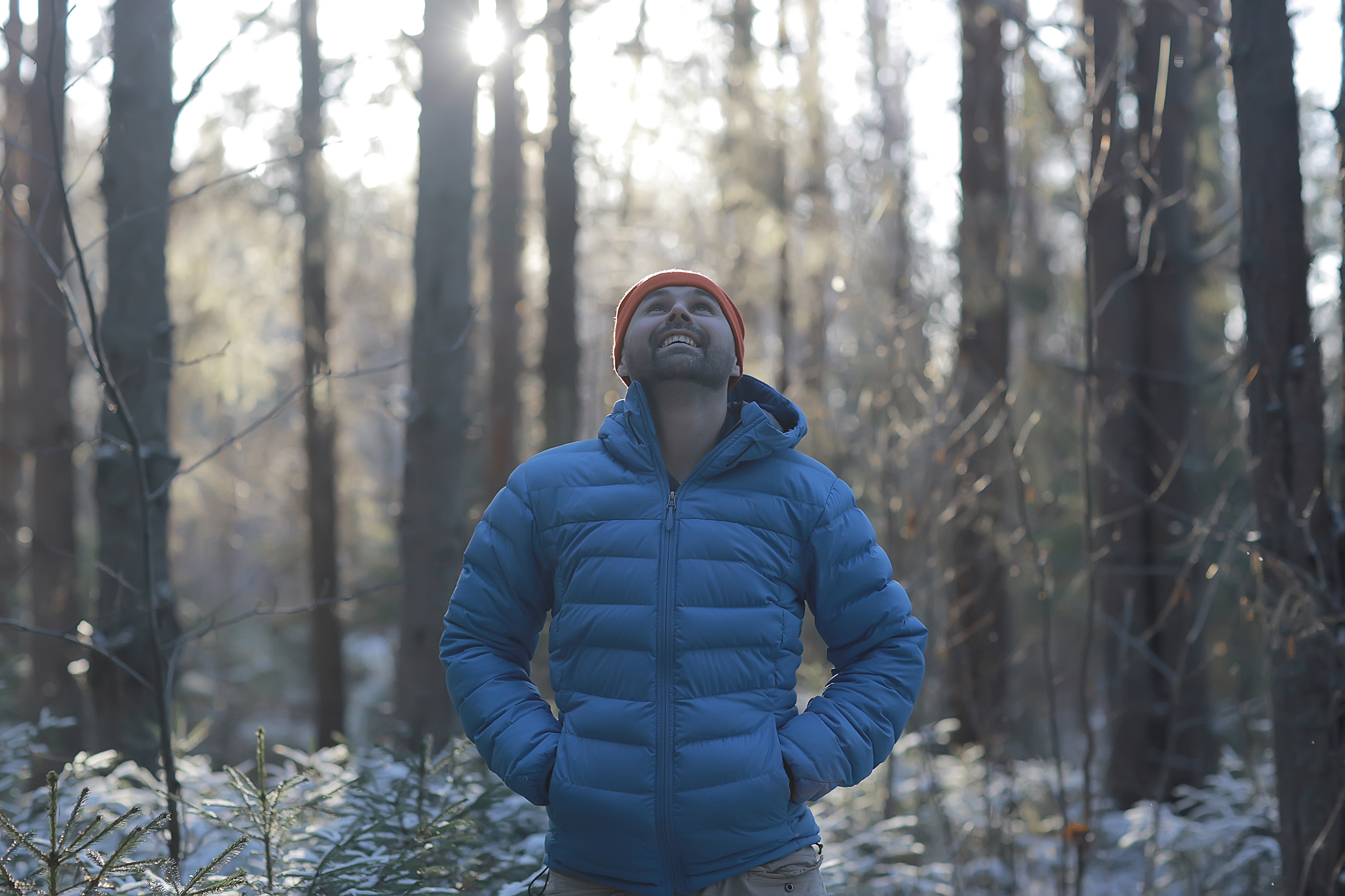 Ein Mann mit einer Daunenjacke in einem winterlichen Wald.