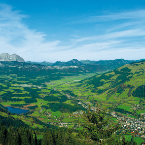 Kitzbühel mit seinem alpinen Wahrzeichen, dem Kitzbüheler Horn; links ein Teil des Wilden Kaisers, in der Mitte Berge der Chiemgauer Alpen, rechts ein paar Hörner der Loferer Steinberge