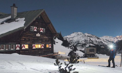 Im Hintergrund der Südwiener Hütte erhellen die Lichter des Wintersportzentrums Obertauern die Nacht.